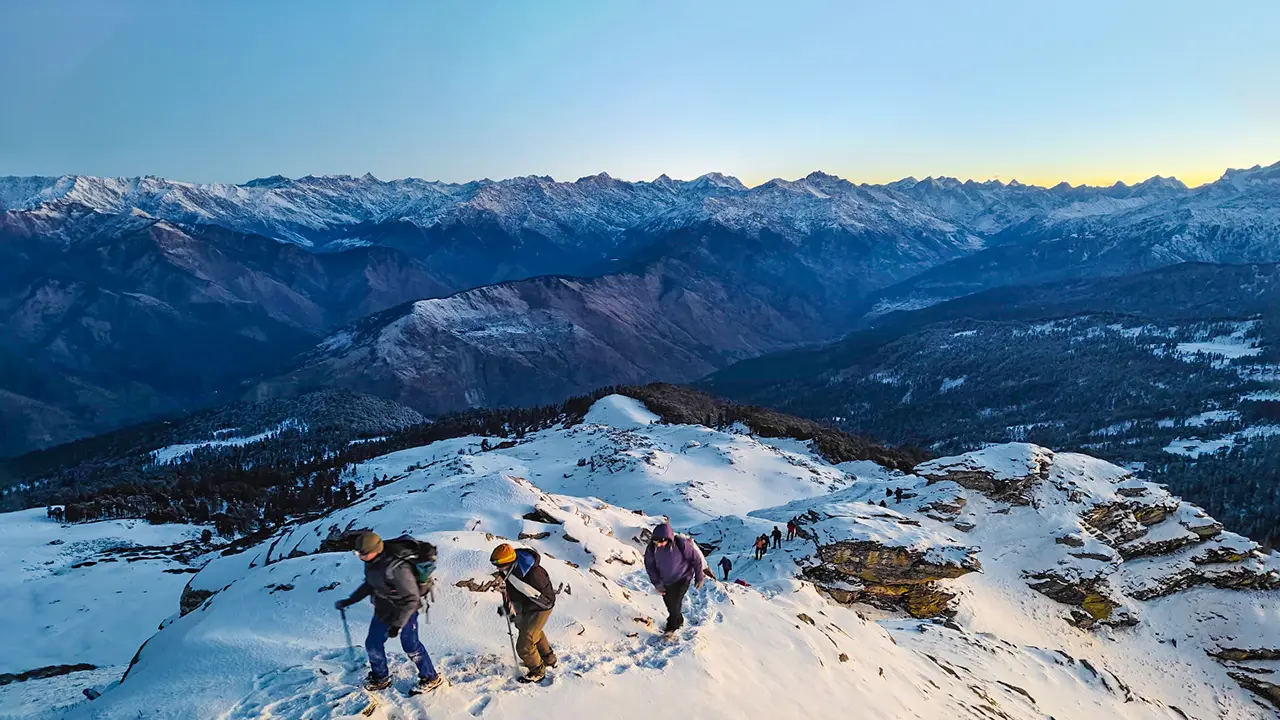 Trekkers walking on a snowy trail during the Kedarkantha Trek