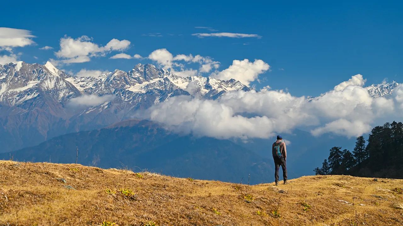 Trekker is standing and enjoying the view of snow peaks during dayara bugyal