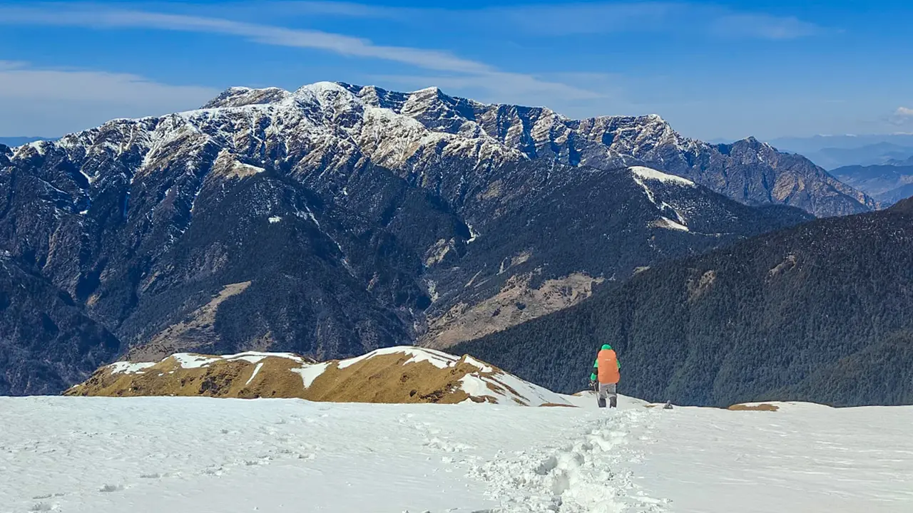 Trekker is enjoying the view of snow capped peak during ali bedni trek
